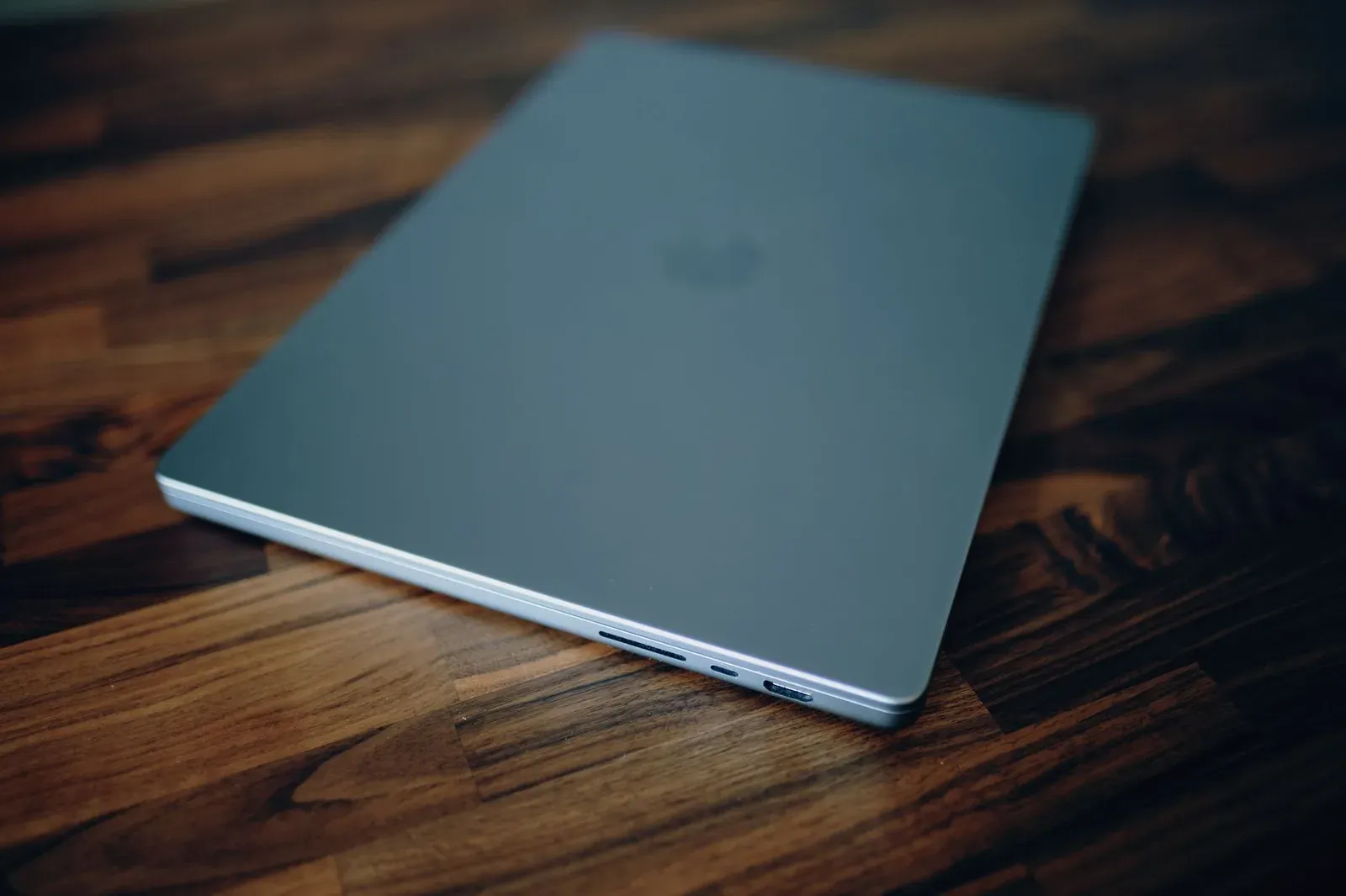 Closed laptop on a polished wooden table, emphasizing clean design and technology.