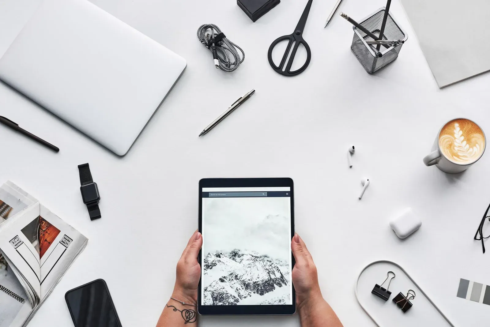 Flat lay of a modern workspace featuring a tablet, gadgets, and coffee for creative work.