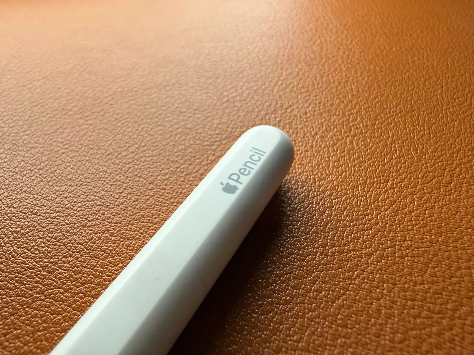 Close-up of a white stylus on an orange textured surface, perfect for design themes.