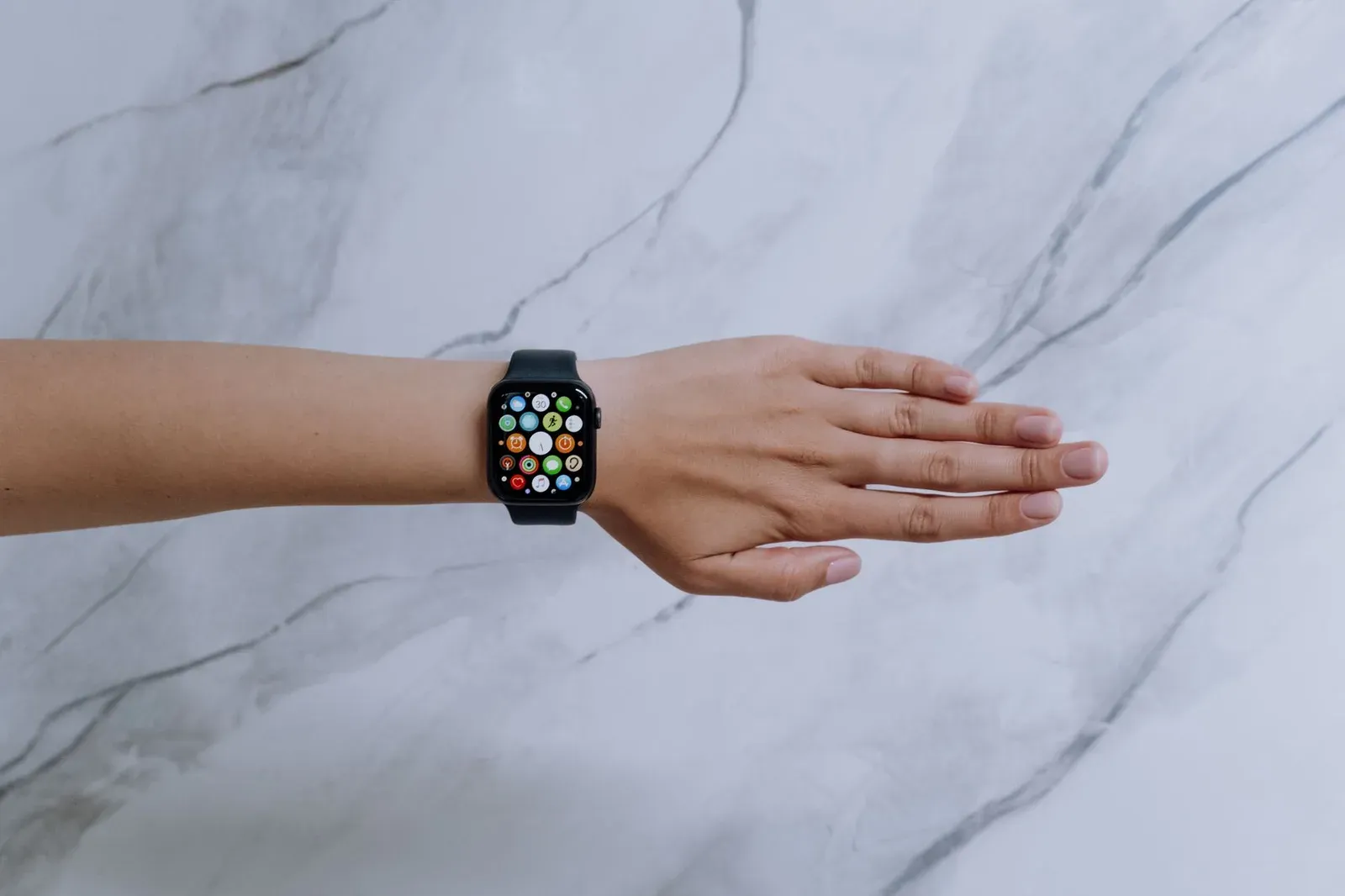 Overhead view of a smartwatch on an arm against a marble background representing modern technology.