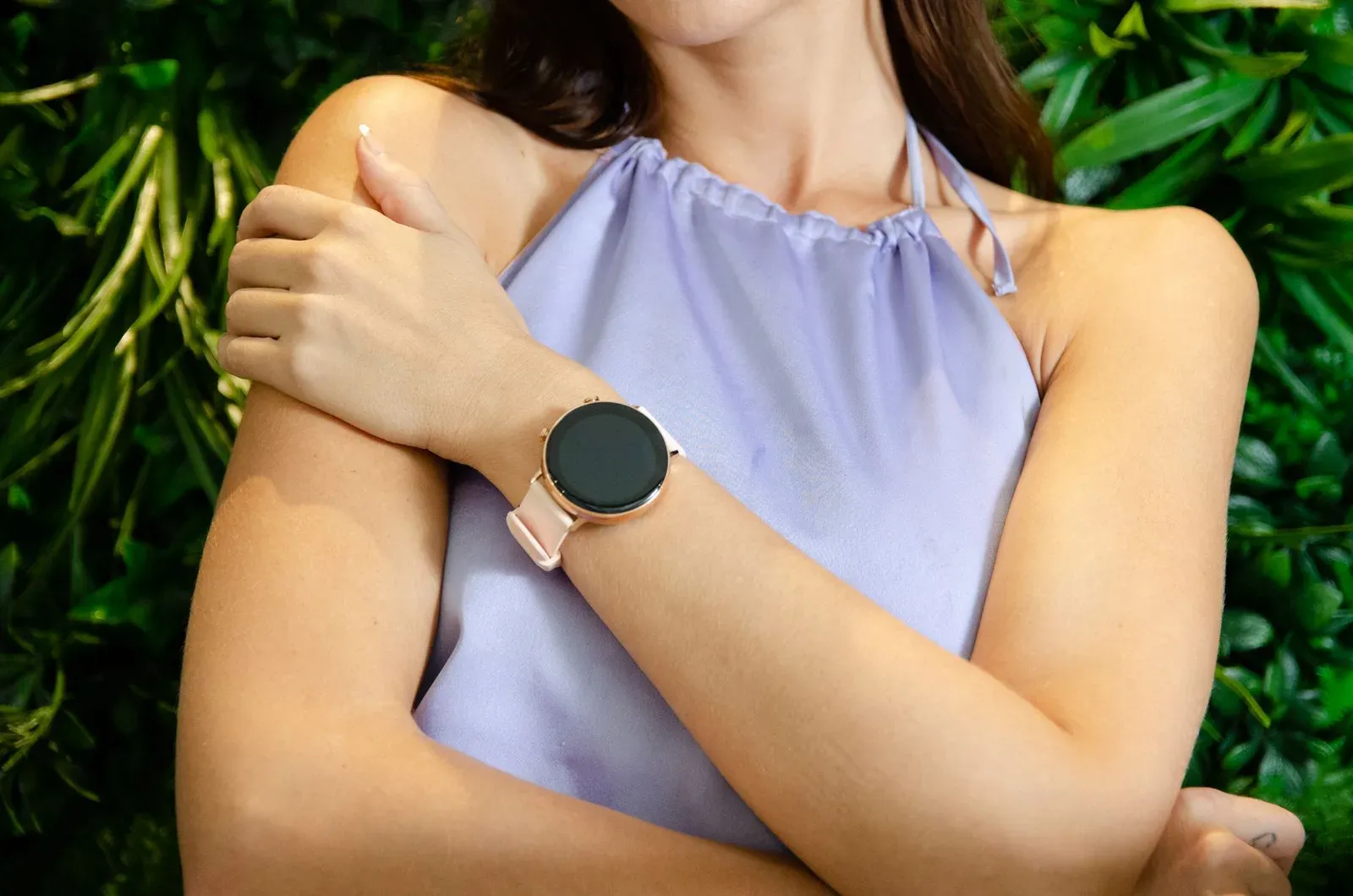 A woman wearing a modern smartwatch with a garden background, showcasing elegance and technology.